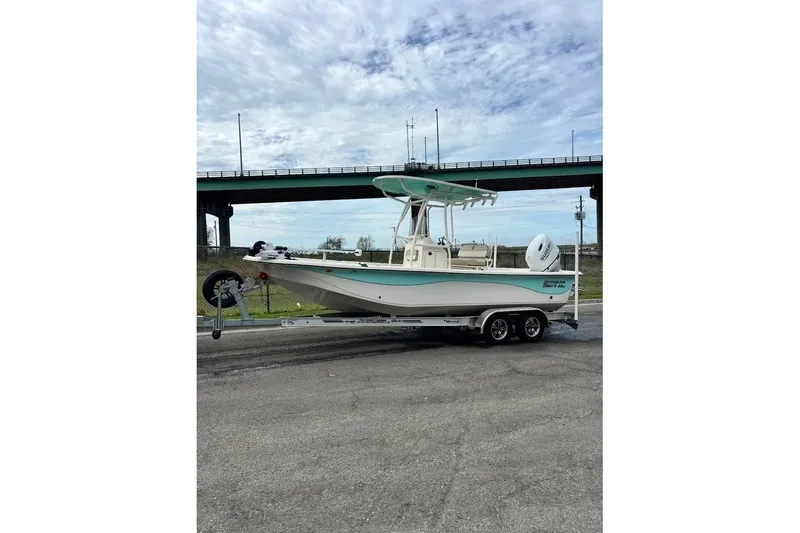 Slide: The Image of 2024 Carolina Skiff 23 LS boat on trailer, parked under a cloudy sky. - 4