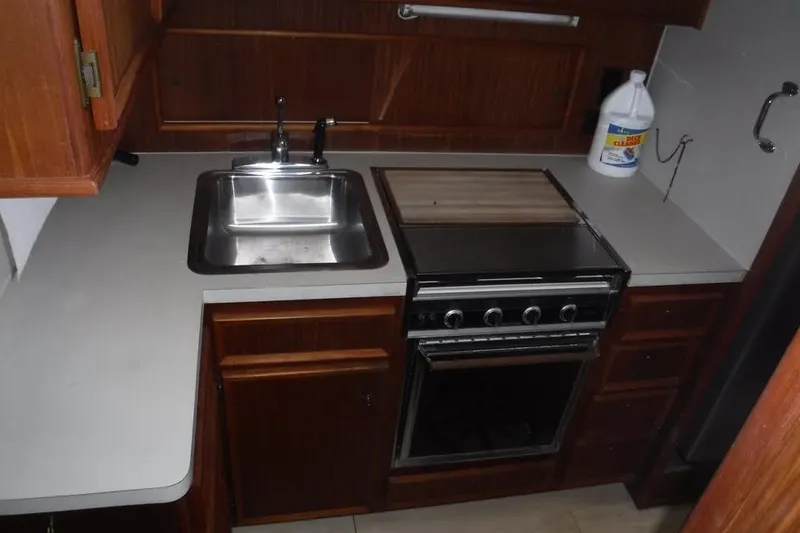 Slide: The Image of 1979 Hatteras 46 Convertible yacht kitchen with sink, stove, and wooden cabinetry. - 7