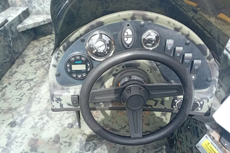 Slide: The Image of Steering console of 2021 Excel 1860 Stalker SC boat with camo design and control gauges. - 13