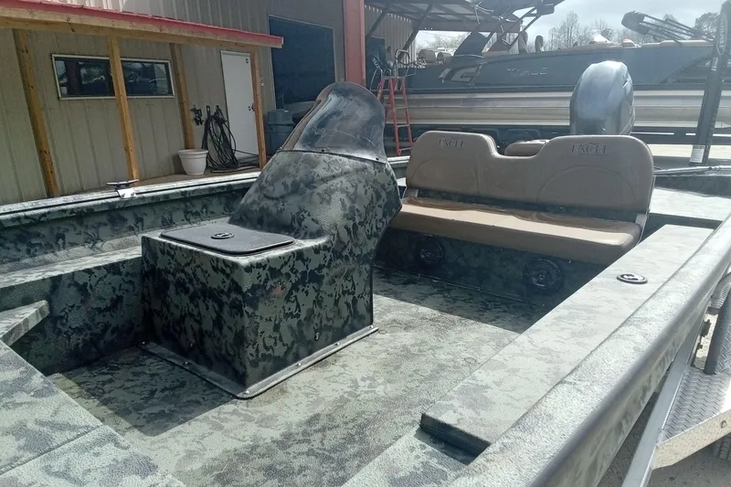 Slide: The Image of 2021 Excel 1860 Stalker SC boat with camouflage interior, parked near a building. - 6