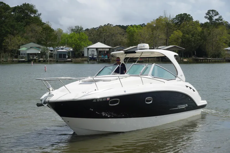 Slide: The Image of 2014 Chaparral 330 Signature boat cruising on a calm lake near shoreline homes. - 10