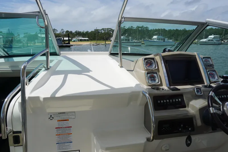 Slide: The Image of 2014 Chaparral 330 Signature boat dashboard with gauges and steering wheel, docked at marina. - 26