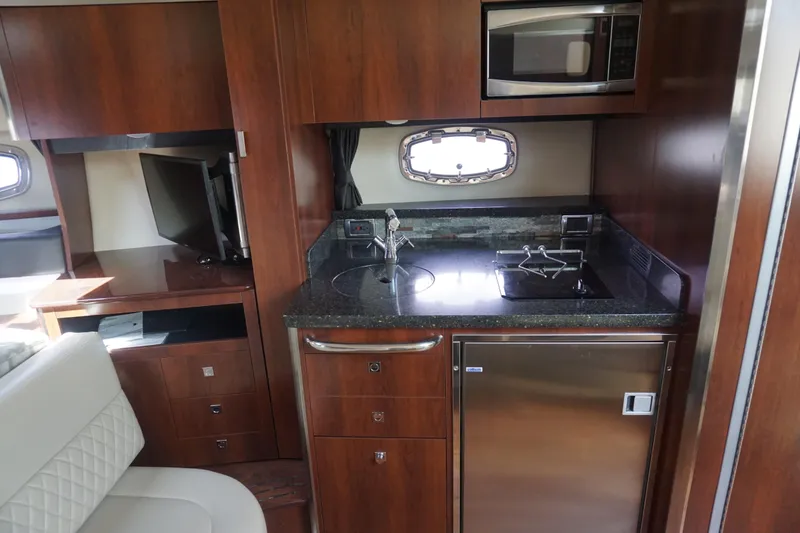 Slide: The Image of 2014 Chaparral 330 Signature yacht interior with kitchenette, featuring microwave and compact fridge. - 30