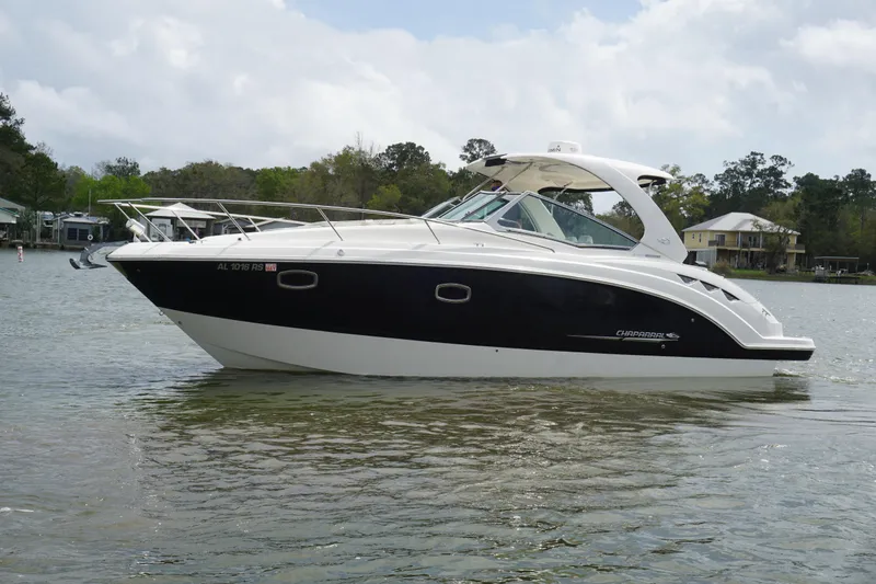 Slide: The Image of 2014 Chaparral 330 Signature boat on calm water, surrounded by trees and houses. - 5