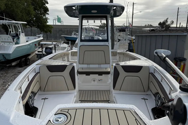 Slide: The Image of 2021 Yamaha Boats 255 FSH Sport E interior with seating and helm, docked outdoors. - 4