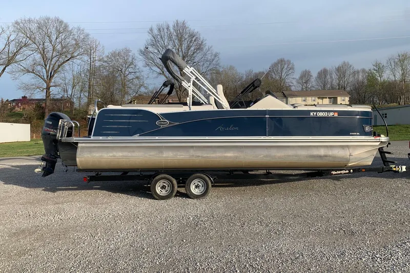 Slide: The Image of 2018 Avalon 2585 Catalina Quad Lounger pontoon boat on trailer, parked outdoors. - 2