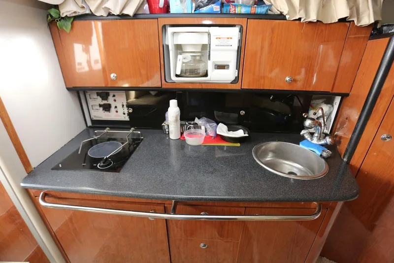 Slide: The Image of Compact kitchen area in a 2000 Chaparral Signature 300 boat, featuring a sink and stove. - 17