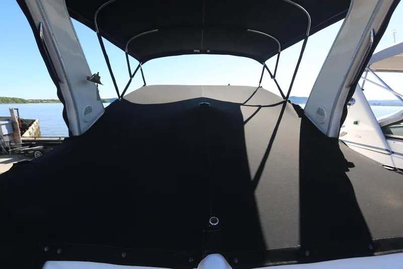 Slide: The Image of 2000 Chaparral Signature 300 boat with black canvas cover, docked by the water. - 63