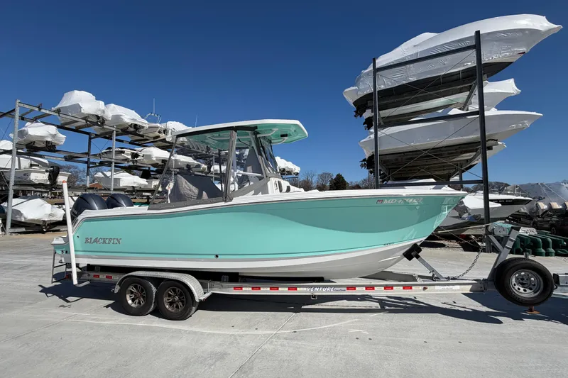 Slide: The Image of 2020 Blackfin 242 CC boat on trailer, turquoise hull, stored outdoors under clear blue sky. - 21