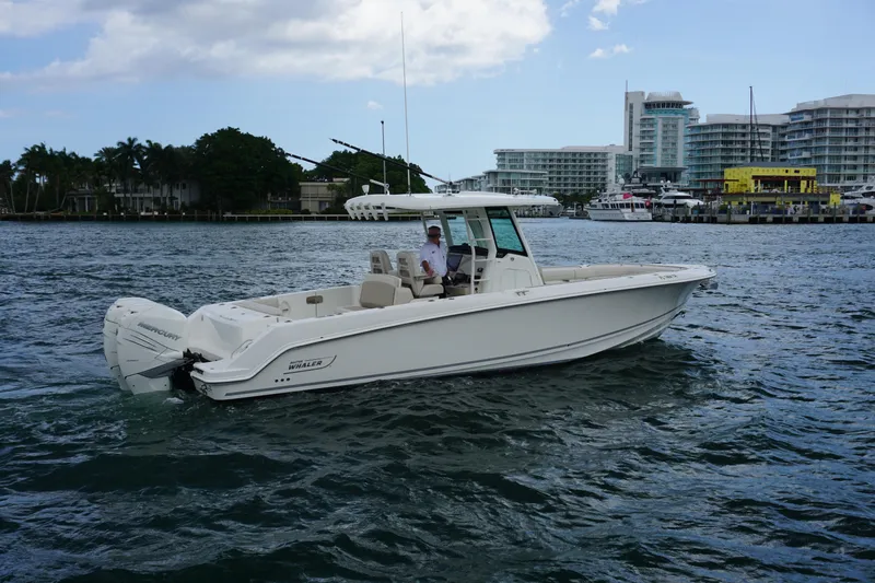 Slide: The Image of 2018 Boston Whaler 330 Outrage boat cruising on water near urban waterfront. - 13