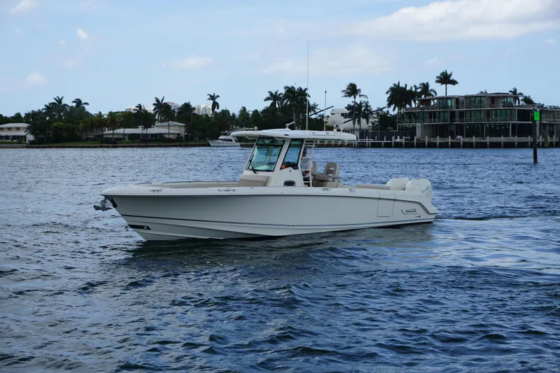 Slide: The Image of 2018 Boston Whaler 330 Outrage cruising on a scenic waterway with palm trees. - 2