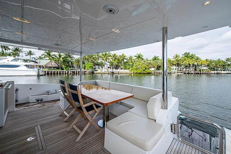 Slide: The Image of Luxurious 2017 Azimut 80 yacht deck with seating, overlooking serene waterfront and palm trees. - 15