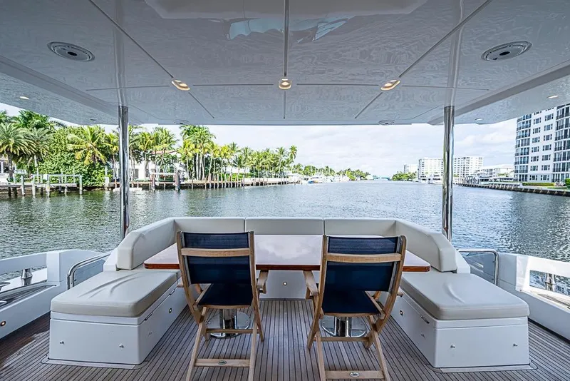 Slide: The Image of Luxurious 2017 Azimut 80 yacht deck with seating, overlooking serene waterfront and palm trees. - 18