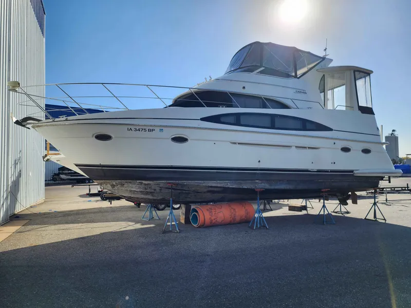 The Image of 2001 Carver 396 yacht dry-docked under sunny skies. - 1