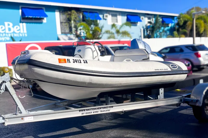 The Image of 2021 Walker Bay Generation 340 inflatable boat on trailer, parked in sunny lot. - 0