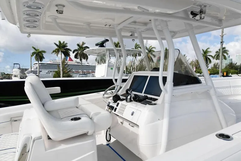 Slide: The Image of 2022 Intrepid 345 Nomad FE boat interior with helm, palm trees, and cruise ship in background. - 11