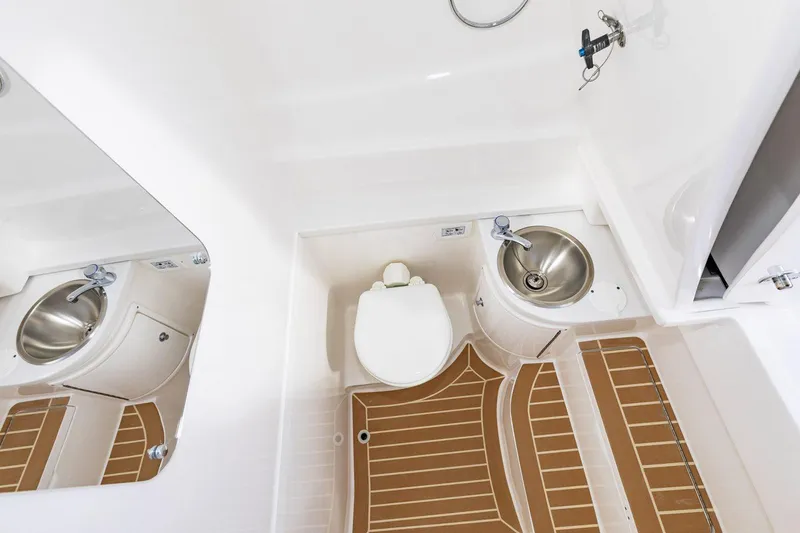 Slide: The Image of Manufacturer Provided Image: 2022 Intrepid 345 Nomad FE boat bathroom with toilet, sink, and wooden floor mat. - 19