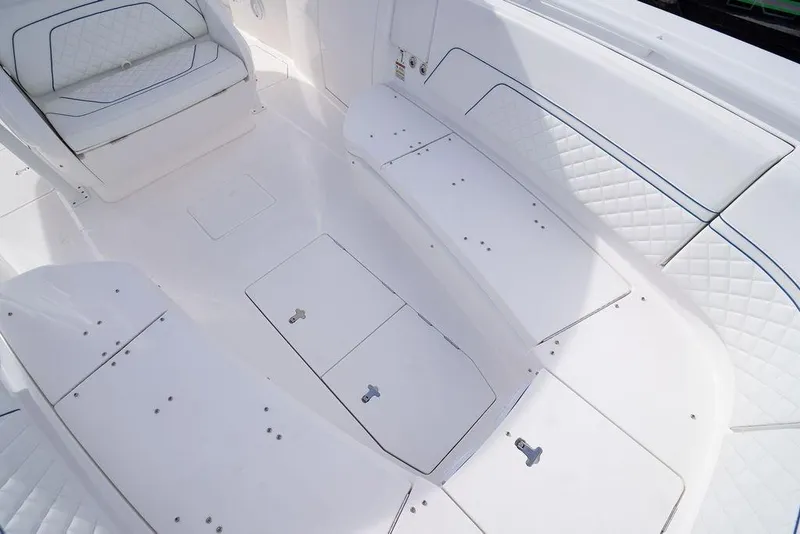 Slide: The Image of 2022 Intrepid 345 Nomad FE boat interior with white cushioned seating and storage compartments. - 33