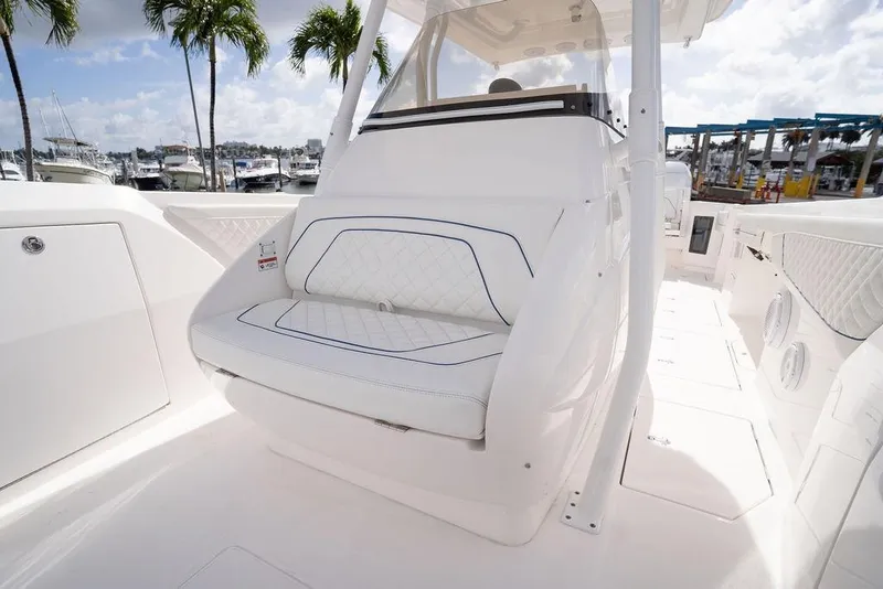 Slide: The Image of 2022 Intrepid 345 Nomad FE boat interior with white seating and marina view. - 34