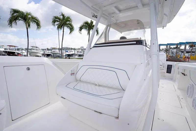 Slide: The Image of 2022 Intrepid 345 Nomad FE boat interior with white seating and palm trees in background. - 35