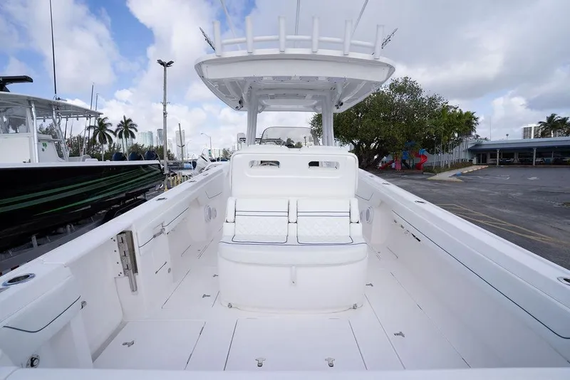 Slide: The Image of 2022 Intrepid 345 Nomad FE boat interior with seating and helm, docked under cloudy sky. - 40