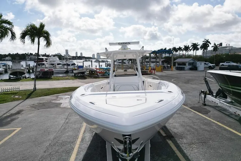 Slide: The Image of 2022 Intrepid 345 Nomad FE boat docked at a marina with palm trees and cloudy sky. - 5