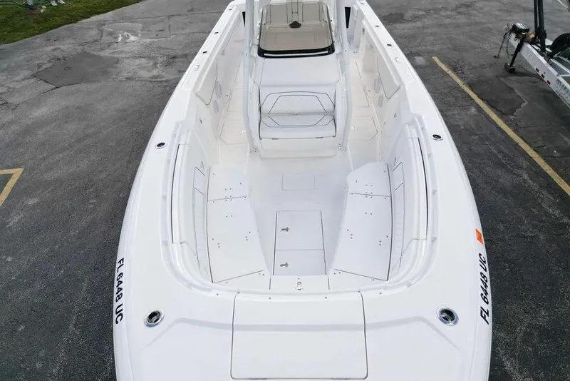 Slide: The Image of 2022 Intrepid 345 Nomad FE boat, spacious deck view, white interior, parked on pavement. - 7