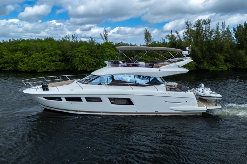 The Image of 2012 Prestige Flybridge yacht cruising on a serene waterway with lush greenery. - 0