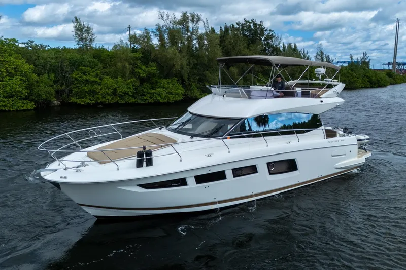 Slide: The Image of 2012 Prestige Flybridge yacht cruising on a scenic waterway with lush greenery. - 2