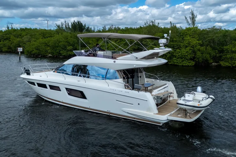 Slide: The Image of 2012 Prestige Flybridge yacht cruising on a scenic waterway with lush greenery. - 3