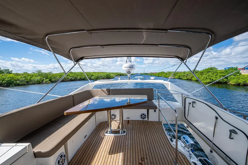 Slide: The Image of 2012 Prestige Flybridge yacht with spacious deck, elegant seating, and scenic waterway view. - 31