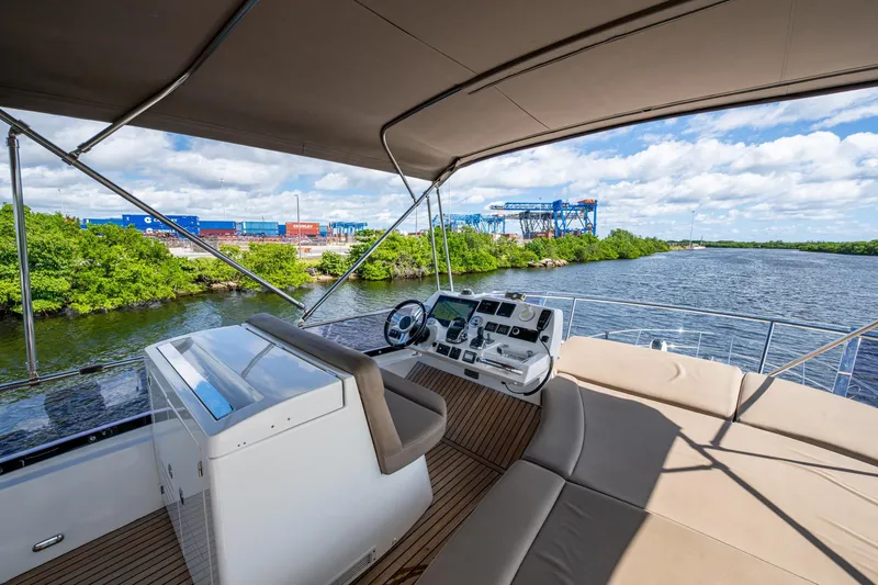 Slide: The Image of 2012 Prestige Flybridge yacht helm with river view, featuring modern controls and comfortable seating. - 39