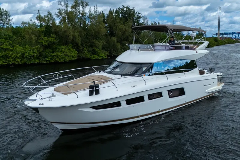 Slide: The Image of 2012 Prestige Flybridge yacht cruising on a scenic waterway with lush greenery. - 5