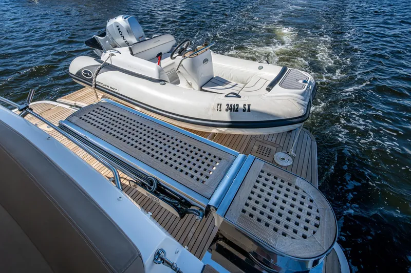 Slide: The Image of 2012 Prestige Flybridge yacht with inflatable boat on water, featuring teak deck. - 62
