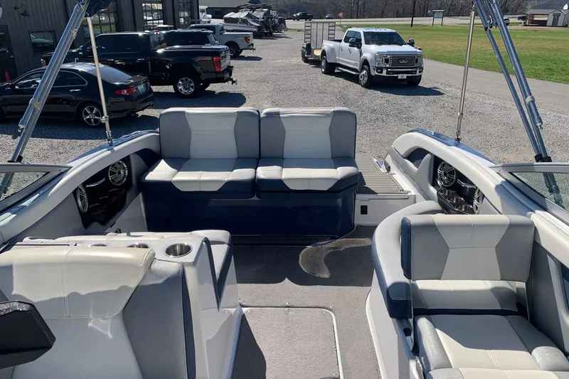 Slide: The Image of 2015 Bryant Calandra boat interior with plush seating and cup holders, parked near vehicles. - 14