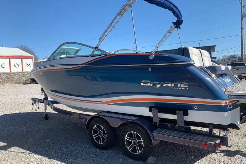 Slide: The Image of 2015 Bryant Calandra boat on trailer, blue and white with orange accents, parked outdoors. - 3