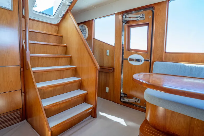 Slide: The Image of Luxurious interior of 2001 Symbol 62 Pilothouse Yacht with wooden stairs and seating area. - 26