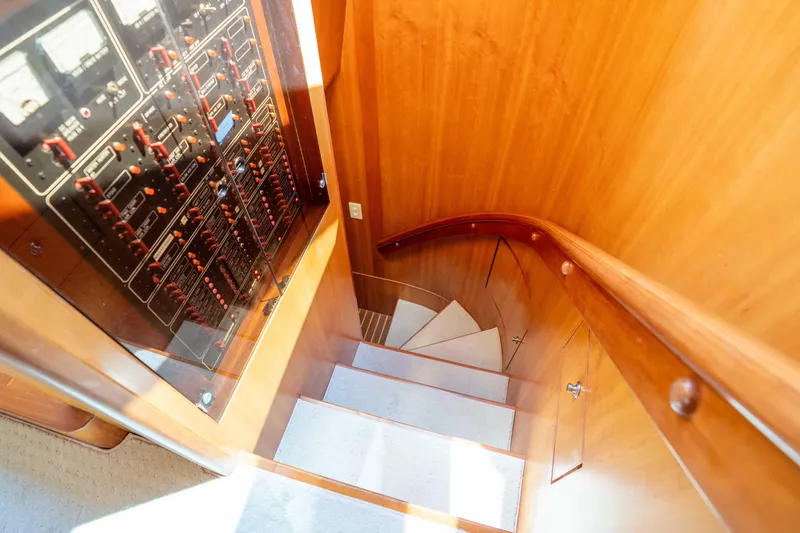 Slide: The Image of Staircase and control panel inside 2001 Symbol 62 Pilothouse Yacht, featuring wooden interior. - 27