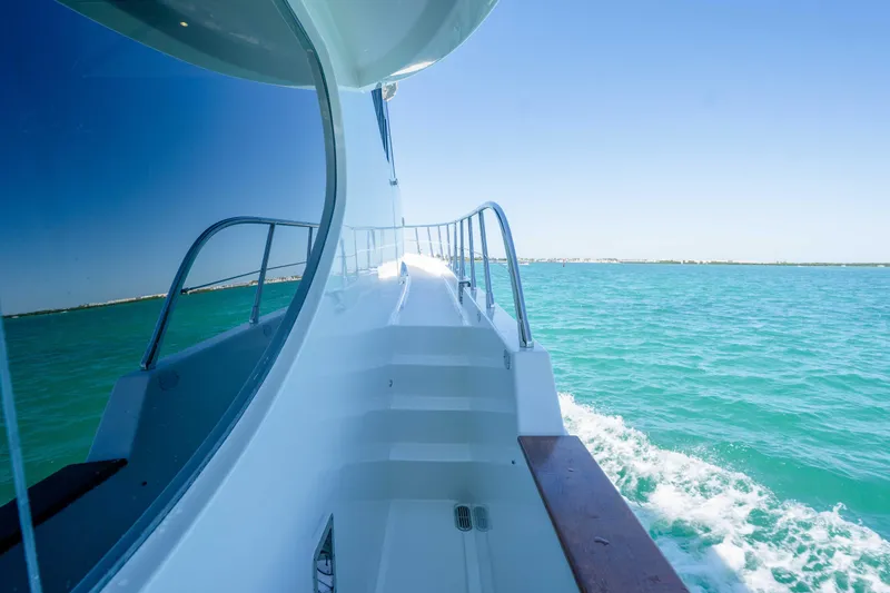 Slide: The Image of Side view of a 2001 Symbol 62 Pilothouse Yacht cruising on turquoise waters. - 34
