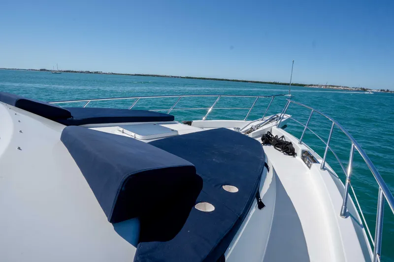 Slide: The Image of 2001 Symbol 62 Pilothouse Yacht deck with blue cushions, cruising on clear blue waters. - 35