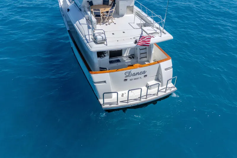 Slide: The Image of 2001 Symbol 62 Pilothouse Yacht on clear blue water, rear view with American flag. - 8
