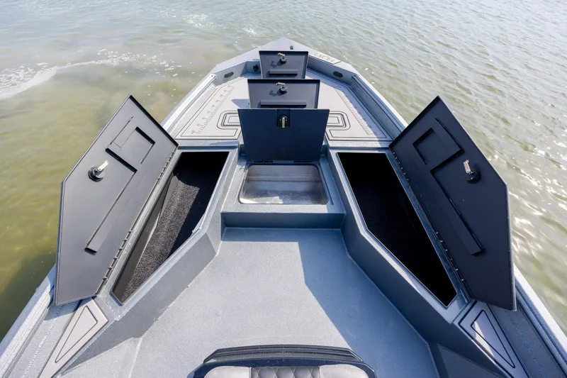 Slide: The Image of 2026 Excel 220 Bay Pro Elite boat with open storage compartments on calm water. - 10