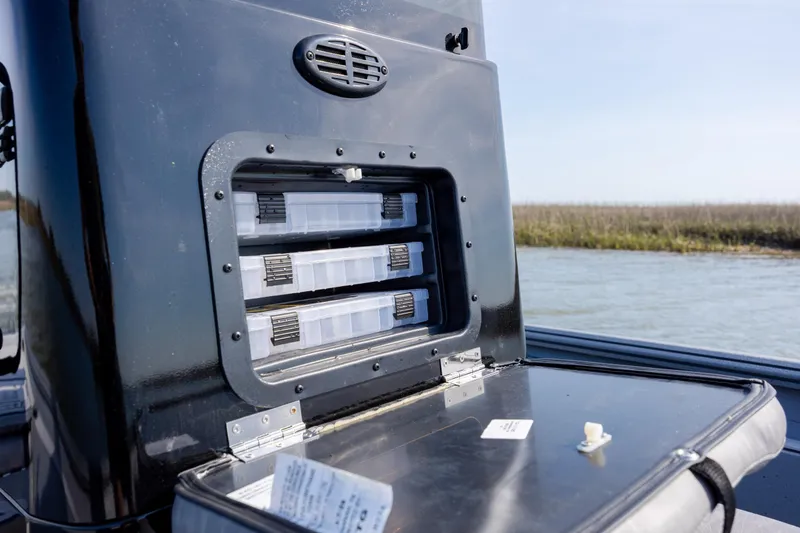 Slide: The Image of Storage compartment on 2026 Excel 220 Bay Pro Elite boat, featuring organized tackle boxes. - 21