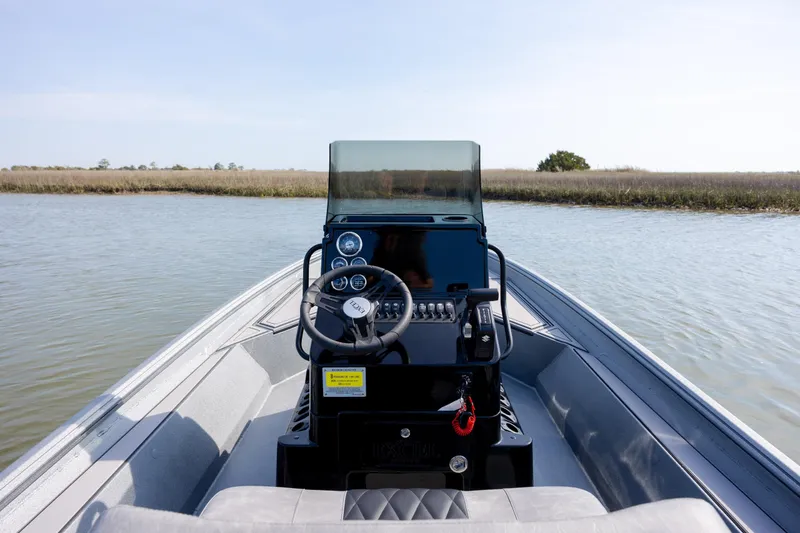 Slide: The Image of 2026 Excel 220 Bay Pro Elite boat on calm water, showcasing steering console and dashboard. - 23