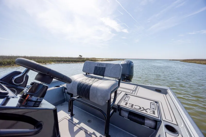Slide: The Image of 2026 Excel 220 Bay Pro Elite boat on calm water, featuring sleek seating and steering. - 26