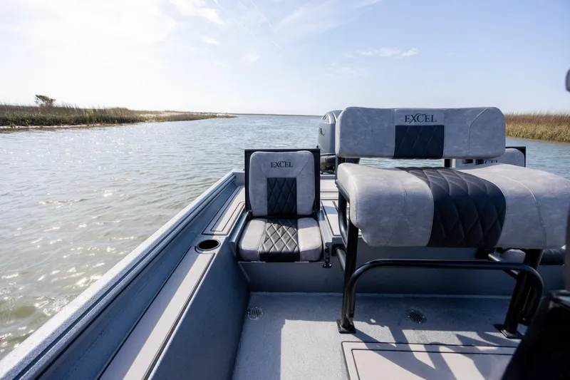 Slide: The Image of 2026 Excel 220 Bay Pro Elite boat interior with cushioned seating on a calm waterway. - 28
