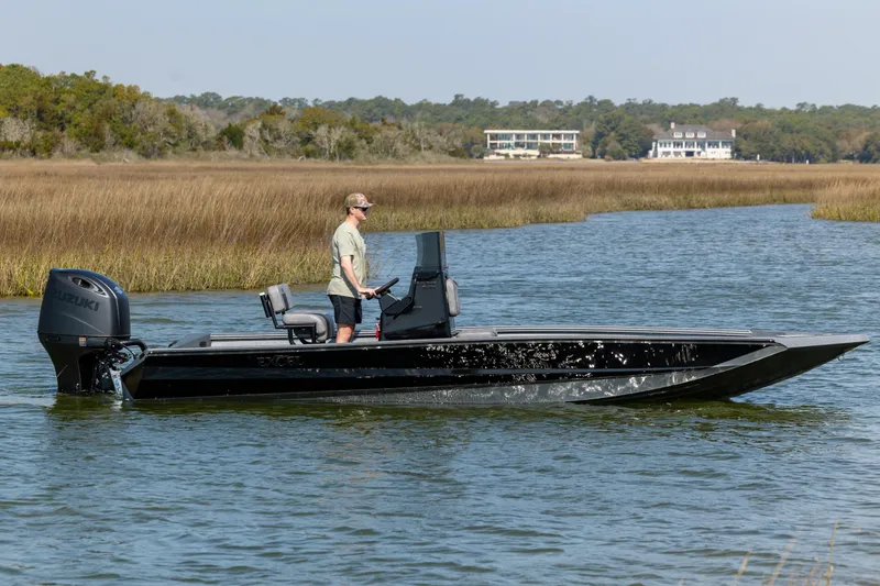 Slide: The Image of 2026 Excel 220 Bay Pro Elite boat cruising on a serene waterway with scenic background. - 3