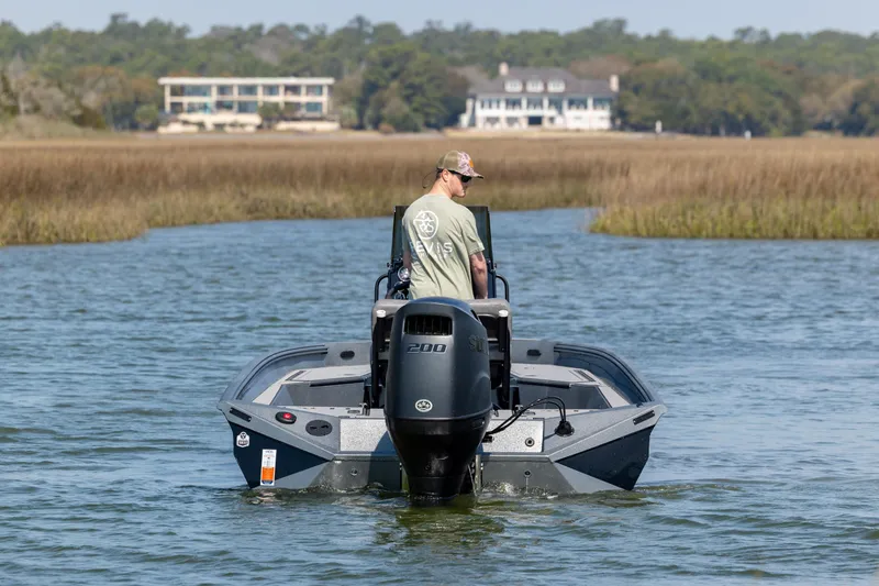 Slide: The Image of Man steering 2026 Excel 220 Bay Pro Elite boat on a calm waterway. - 6