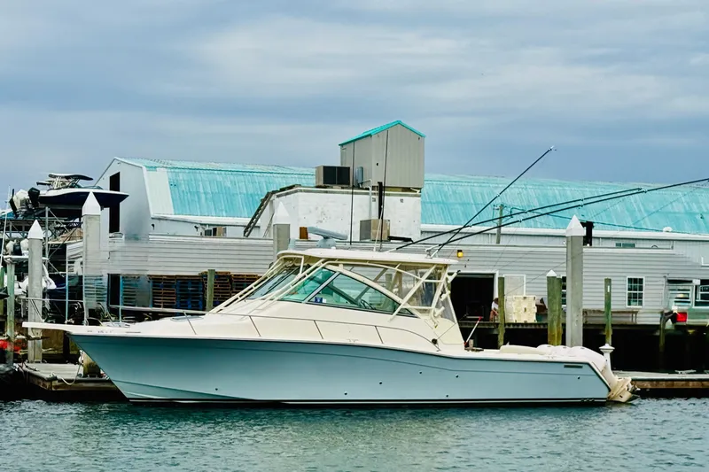 The Image of 2015 Grady-White Express 370 boat docked at marina with blue-roofed buildings. - 0
