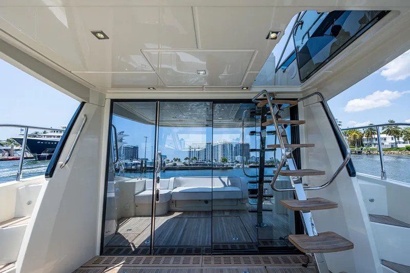 Slide: The Image of 2015 Beneteau MONTE CARLO yacht interior with glass doors and wooden steps, overlooking water. - 16